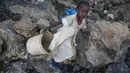 Irene Wanzila, 10, membawa seember batu pecah setelah ibunya yang kehilangan pekerjaan sebagai petugas kebersihan di sekolah swasta ketika pembatasan pandemi virus corona diberlakukan, di tambang Kayole di Nairobi, Kenya, 29 September 2020.  (AP Photo/Brian Inganga)