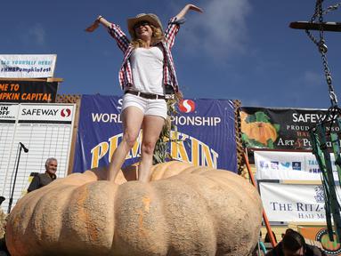 Cindy Tobeck berdiri di atas labu seberat 1.736 pon miliknya dalam lomba Safeway World Championship Pumpkin Weigh-Off di Half Moon Bay, California, Amerika Serikat, Senin (14/10/2019). Seorang petani keluar sebagai juara dengan labu seberat 2.175 pon miliknya. (Justin Sullivan/Getty Images/AFP)