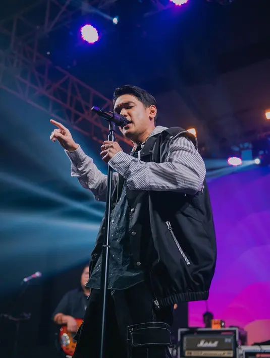 Aksi panggung keren Afgan juga tak boleh dilewatkan. Di foto ini, Afgan tampil edgy chic mengenakan oversized hoodie short biru bercorak garis, ditumpuknya dengan vest jacket parasut berwarna hitam, dan dipadukan dengan cargo pants hitam. [Foto: Instagram/afganisme.official]