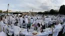 Orang-orang berpakaian putih berkumpul bersiap untuk makan malam bersama atau "Diner en Blanc" yang ke-30 di Paris, Prancis (3/6). Tempat dilaksanakannya acara ini akan dirahasiakan oleh penyelenggara hingga 2-1 jam sebelum dimulai. (AFP/Francois Guillot)