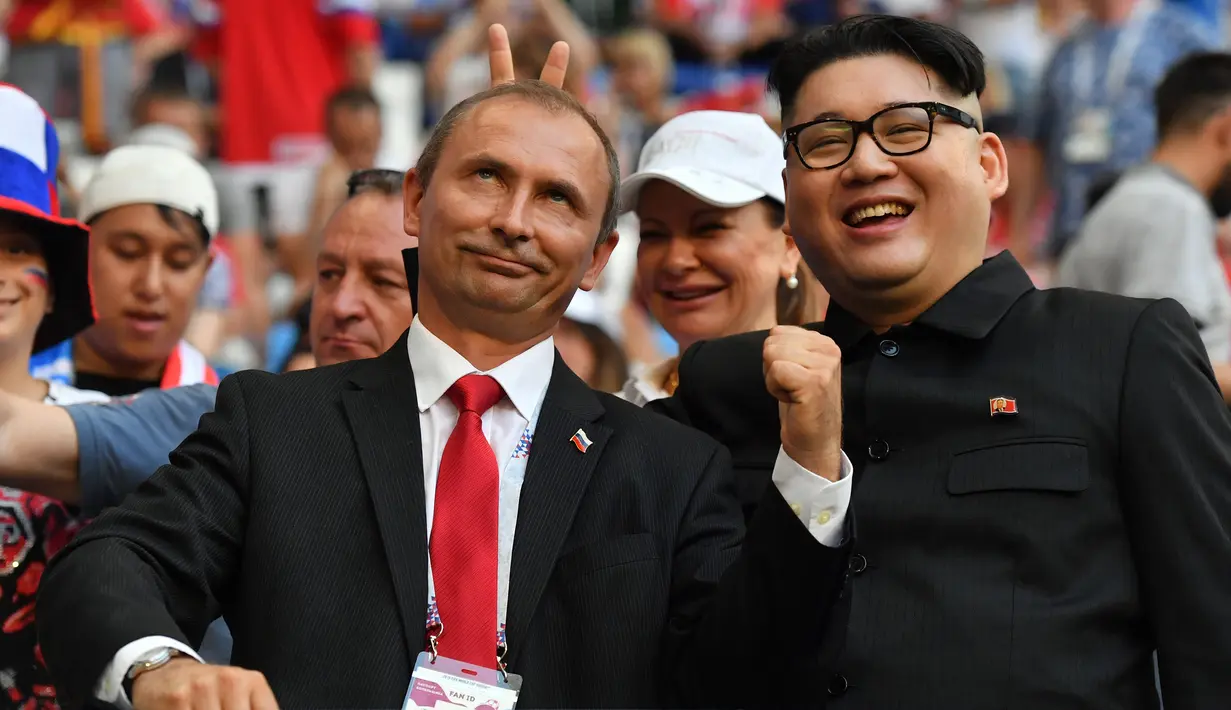 Peniru Presiden Rusia, Vladimir Putin dan pemimpin Korea Utara, Kim Jong-un berpose selama menyaksikan laga penyisihan Grup A Piala Dunia 2018 antara Uruguay vs Rusia di Samara Arena, Senin (25/6). Uruguay berhasil melumat Rusia 3-0. (AFP/EMMANUEL DUNAND)