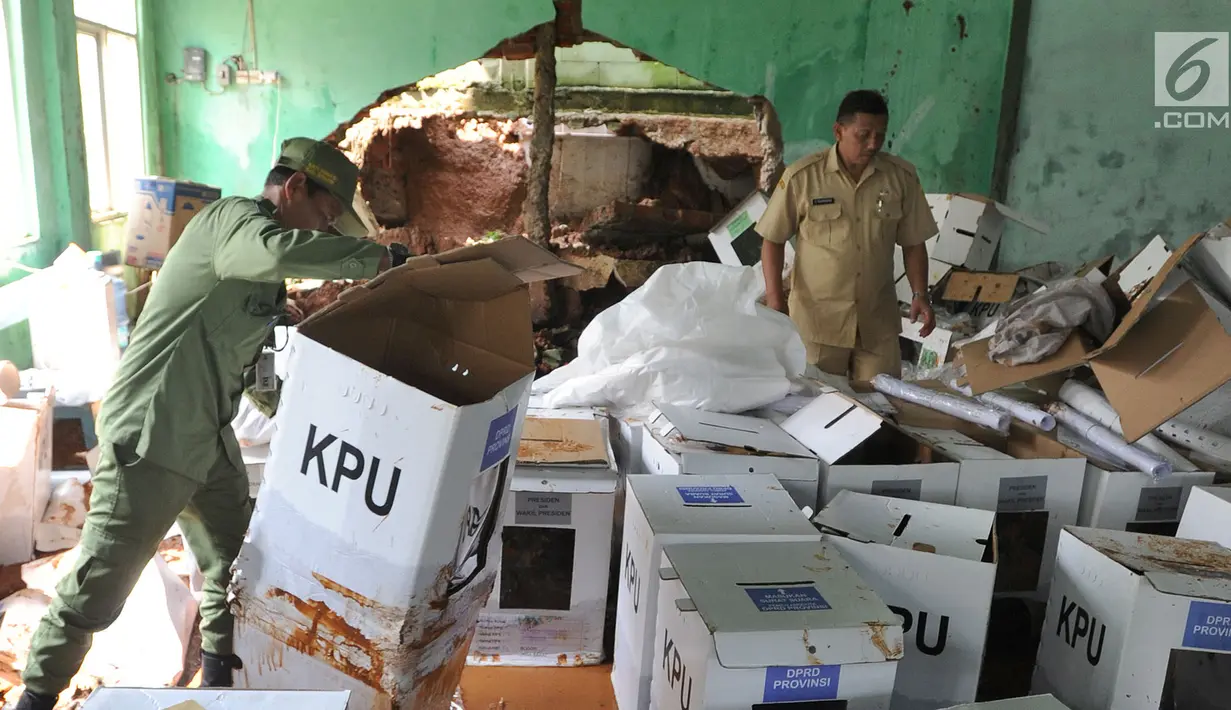 Petugas kecamatan menyelamatkan kotak suara kardus yang sebagian rusak terendam banjir di gudang tempat penyimpanan logistik di Kecamatan Ciseeng, Bogor, Senin (15/4). Lebih dari 600 kotak suara rusak akibat tembok gudang jebol diterpa hujan lebat dan angin kencang semalam. (merdeka.com/Arie Basuki)