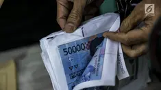 Petugas Direktorat Tindak Pidana Ekonomi Khusus Bareskrim Polri memperlihatkan uang palsu saat rilis di Bareskrim Polri, Jakarta, Jumat (16/6). Bareskrim Mabes Polri menangkap seorang pembuat uang palsu bernama Muhammad Amin. (Liputan6.com/Faizal Fanani)