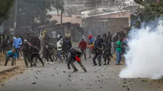 Para pengunjuk rasa melempari polisi dengan batu saat terjadi bentrokan di samping awan gas air mata di daerah Kibera, Nairobi, Kenya, Rabu, 19 Juli 2023. Warga Kenya kembali melakukan protes di jalan-jalan ibu kota Rabu menentang pajak yang baru diberlakukan dan kenaikan biaya hidup.  (AP Photo/Brian Inganga)