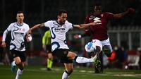 Gelandang Inter Milan, Hakan Calhanoglu (tengah) dan bek Torino Pantai Gading Wilfried Singo (kanan) berebut bola selama pertandingan lanjutan Liga Serie A Italia di stadion Olimpiade di Turin, Senin (14/3/2022). Dengan hasil ini Inter Milan turun ke peringkat ketiga dengan 59 poin. (AFP/Marco Berto