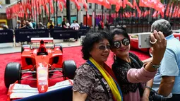 Dua wanita berselfie dengan latar mobil mantan pembalap Ferrari F1, Michael Schumacher di Rockefeller Plaza, New York, AS (8/10). Mobil tersebut pernah memenangkan salah satu seri balapan F1 di Grand Prix Monaco pada tahun 2001. (AFP Photo/Jewel Samad)