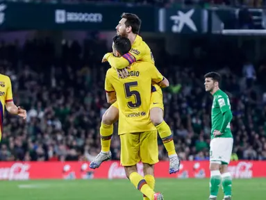 Gelandang Barcelona, Sergio Busquets disambut rekan timnya Lionel Messi usai mencetak gol ke gawang Real Betis pada lanjutan Liga Spanyol pekan ke-23 di Benito Villamarin, Minggu (9/2/2020). Diwarnai dua kartu merah, Barcelona mememangkan duel menegangkan lawan Real Betis 3-2. (AP/Miguel Morenatti)