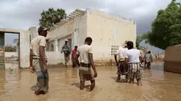 Sejumlah Warga melintasi banjir setelah hujan lebat di sebuah desa di provinsi Laut Merah Yaman, Houdieda, Jumat,  15 April 2016. (REUTERS/Abdul Jabbar Zeyad)