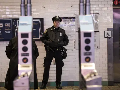 Petugas kepolisian New York berjaga di pintu masuk stasiun kereta bawah tanah Times Square saat jam sibuk malam di New York City, Senin (11/12). Sebelumnya ledakan bom terjadi di terminal bawah tanah kawasan Manhattan. (Drew Angerer/Getty Images/AFP)