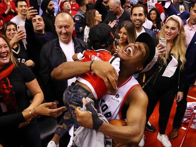 Pebasket Toronto Raptors, Kyle Lowry, menggendong putranya usai mengalahkan Milwaukee Bucks pada NBA Final Wilayah Timur di Scotiabank Arena, Toronto, Sabtu (25/5). Raptors menang 4-2 atas Bucks. (AFP/Gregory Shamus)