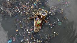 Seorang anak duduk di perahu darurat saat mengumpulkan sampah untuk bahan daur ulang di sebuah sungai yang tercemar di kota navotas, Manila, Kamis (2/7/2015). Daur ulang bertujuan untuk mengurangi tingkat pencemaran sungai. (REUTERS/Romeo Ranoco)