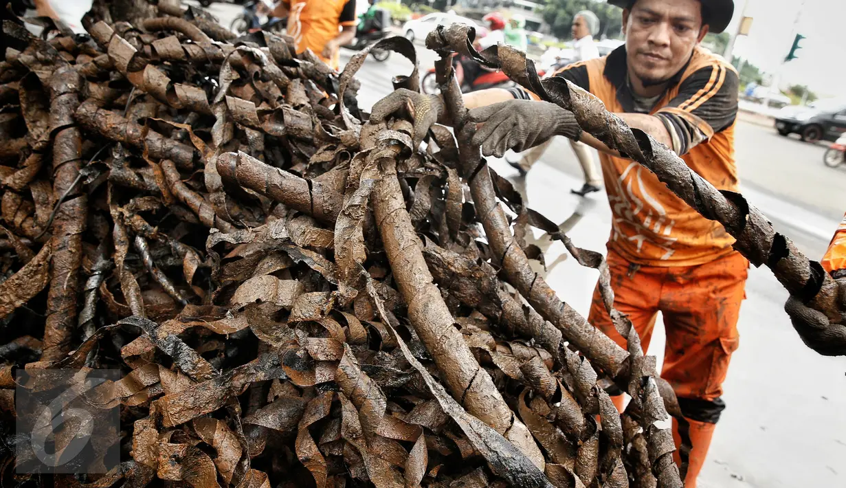 Petugas kebersihan menata bungkusan kabel yang menyumbat saluran air di Jalan Merdeka Selatan, Jakarta, Senin (29/2). Basuki Tjahaja Purnama (Ahok) mengatakan adanya dugaan sabotase banjir akibat limbah kulit kabel itu. (Liputan6.com/Faizal Fanani)