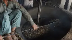 Seorang pedagang Pakistan megaduk kacang pinus  saat dipanggang di pasar di Lahore (13.12). Pakistan merupakan salah satu penghasil kacang pinus terbaik di dunia. (AFP Photo/Arif Ali)
