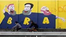 Beberapa warga melintas di depan lukisan grafiti di Sao Paulo, Brasil (3/6/2014). Sao Paulo akan menjadi tuan rumah laga pembukaan Piala Dunia Brasil 2014. (REUTERS/Paulo Whitaker)