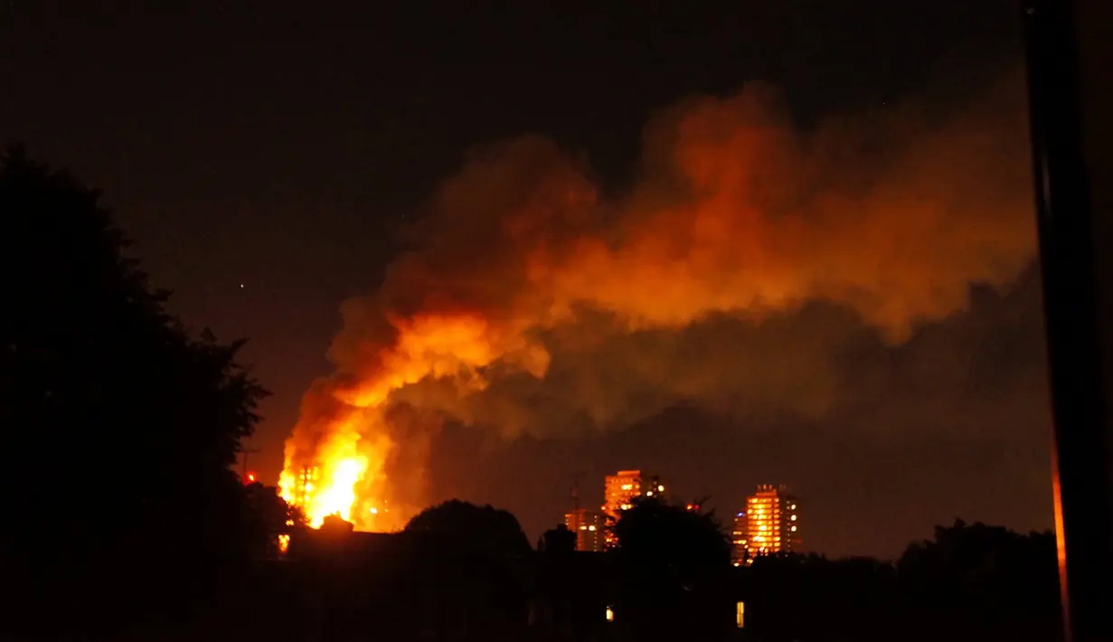 Kepulan asap menyelimuti sebuah apartemen bertingkat 24 lantai yang terbakar di London (14/6). Gedung Grenfell Tower yang terbakar itu berada di kompleks Lancester West Estate. (AFP PHOTO / Jonathan Kelly)