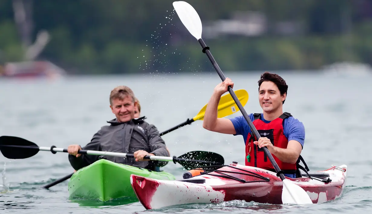 Seorang pria mengamati aksi PM Kanada Justin Trudeau saat mengayuh perahu kayak di sepanjang aliran Sungai Niagara, Ontario, Senin (5/6). Aksi PM Kanada ini untuk memperingati Hari Lingkungan Hidup Sedunia. (Nathan Denette/The Canadian Press via AP)