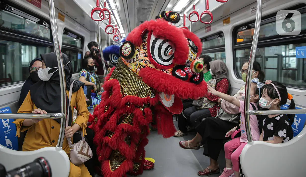 Seorang anak memegang Barongsai yang melakukan atraksi di dalam kereta LTR, Jakarta, Selasa (1/2/2022). Atraksi Barongsai tersebut bertujuan untuk menghibur penumpang LRT dalam rangka menyambut Tahun Baru Imlek. (Liputan6.com/Faizal Fanani)