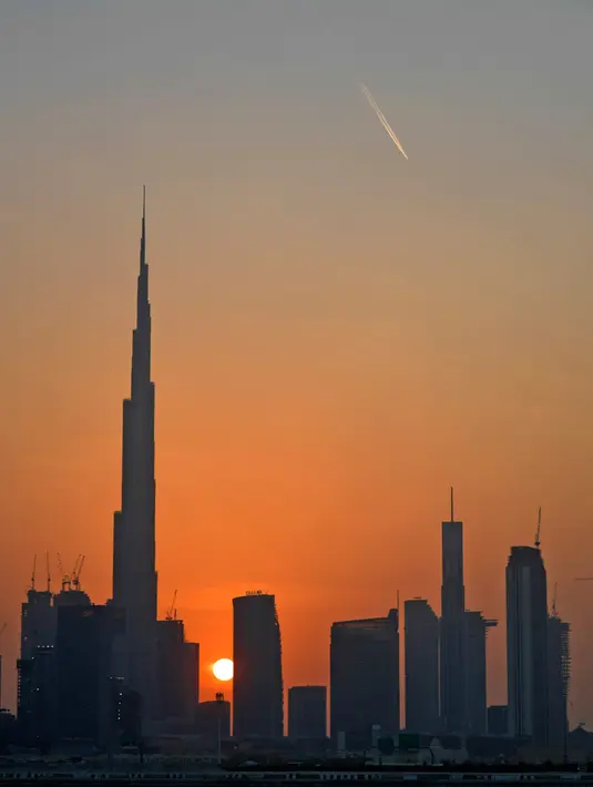 Pemandangan matahari terbenam di belakang Burj Khalifa dan gedung-gedung bertingkat lainnya, di Dubai, Uni Emirat Arab pada Sabtu (12/9/2020). (Photo by Karim SAHIB / AFP)