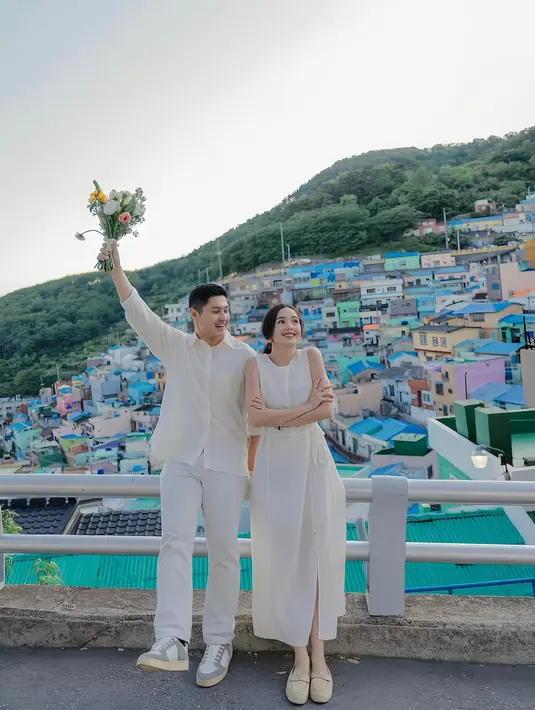 Mengambil latar pemandangan di Busan, Korea Selatan, Rizki Natakusumah tampil kasual mengenakan kemeja lengan panjang dan celana panjang putih. [Foto: Instagram/bebytsabina]