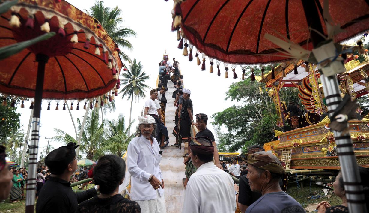Sejumlah warga menyiapkan arak-arakan Bade atau menara bertingkat sembilan yang berisi jenazah anggota keluarga dari pahlawan nasional I Gusti Ngurah Rai dalam prosesi upacara Ngaben di Desa Carangsari, Badung, Bali, Senin (29/4/2019). (SONNY TUMBELAKA/AFP)