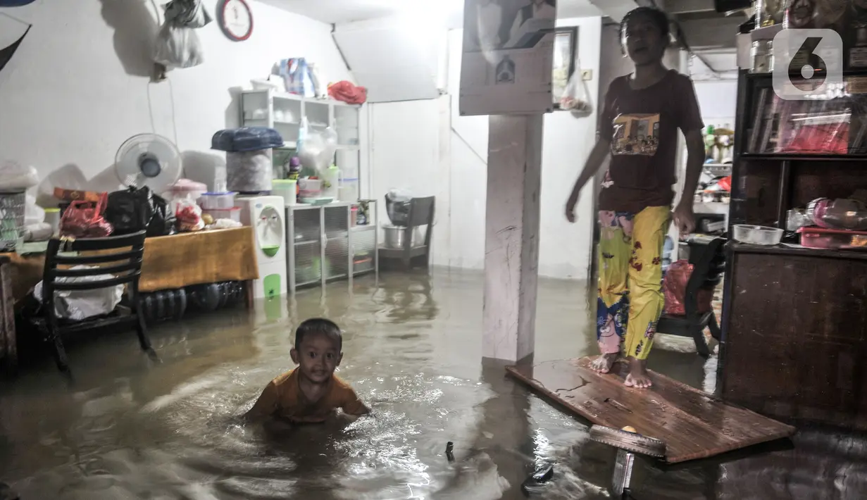 Anak-anak bermain air yang masuk ke dalam rumah di permukiman Bukit Duri, Jakarta, Kamis (18/2/2021). Hujan deras yang mengguyur sejak pagi menyebabkan permukiman warga di 5 RW Kelurahan Bukit Duri terendam banjir hingga mencapai sepinggang orang dewasa. (merdeka.com/Iqbal S Nugroho)