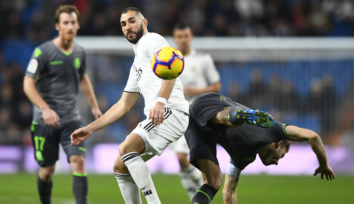 6. Karim Benzema berduel dengan pemain Real Sociedad pada laga lanjutan La Liga Spanyol yang berlangsung di Stadion Santiago Bernabeu, Madrid, Senin (7/1). Real Madrid kalah 0-2 kontra Real Sociedad. (AFP/Gabriel Bouys)