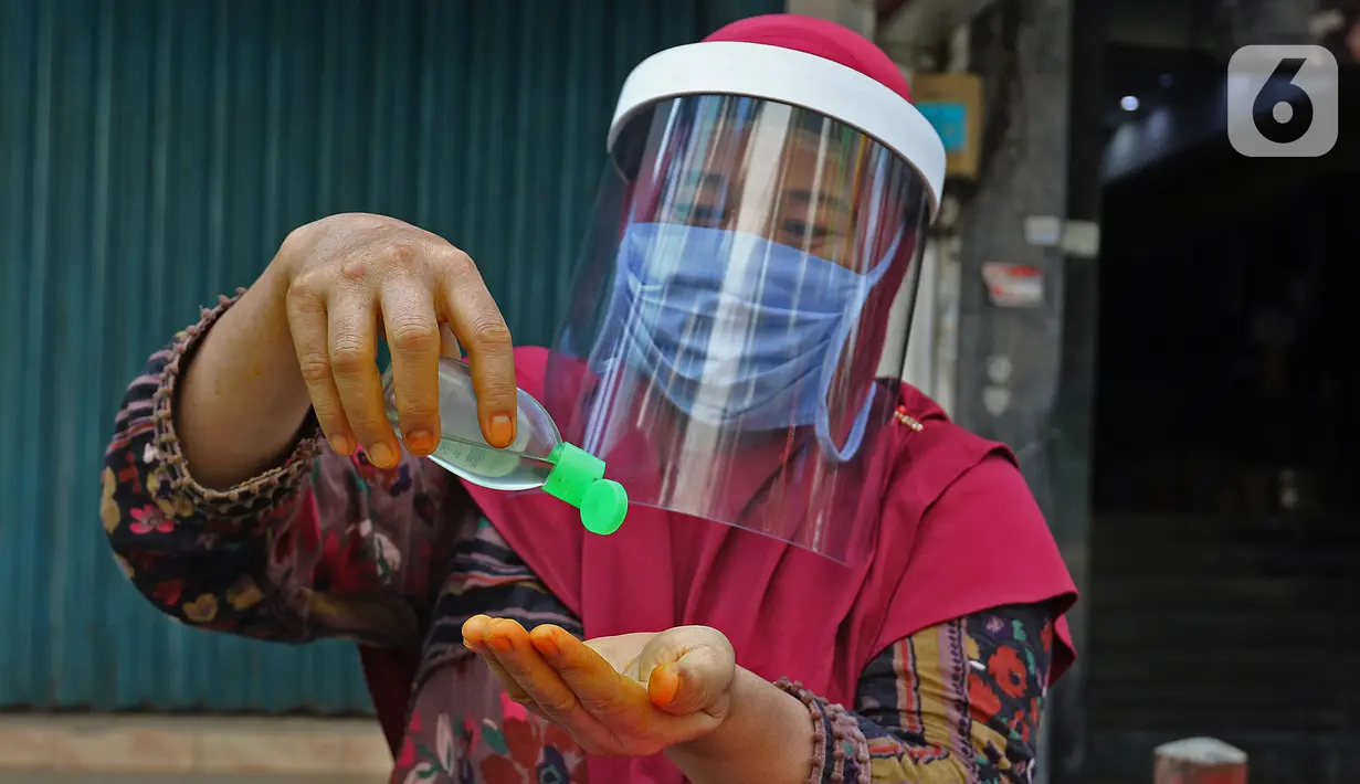 Tidar (46), memakai hand zanitizer di Pasar Baru, Jakarta, Kamis (11/06/2020). Penjual jamu tradisional keliling ini tampak mematuhi protokol kesehatan pencegahan COVID-19 dengan mengenakan masker, face shield, dan sarung tangan dalam melayani pelanggan setianya. (Liputan6.com/Herman Zakharia)