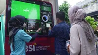 Peserta Mandiri Jogja Marathon 2022 dan pengunjung antre menukarkan botol plastik dengan saldo tabungan BSI melalui Reverse Vending Machine sampah plastik di Ambarukmo, Yogyakarta. (Liputan6.com/HO)