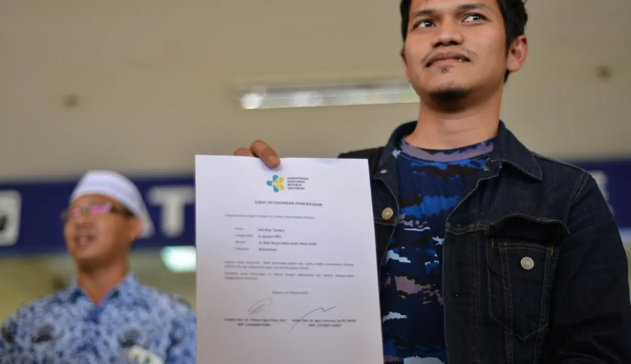 Mahasiswa yang dipulangkan dari karantina virus corona atau COVID-19 di Natuna menunjukkan surat dari Kementerian Kesehatan Indonesia saat tiba di Bandara Internasional Sultan Iskandar Muda, Blang Bintang, Aceh, Senin (17/2/2020). Hari ini, dijadwalkan 8 orang tiba di Aceh. (CHAIDEER MAHYUDDIN/AFP)
