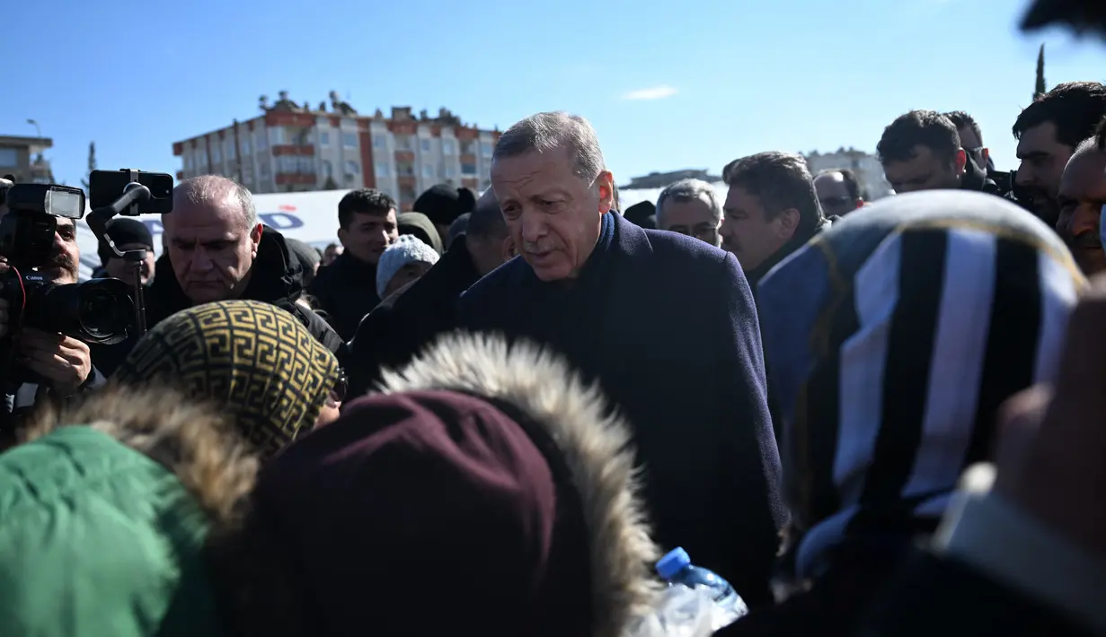 Presiden Turki Recep Tayyip Erdogan bertemu dengan penduduk yang mengungsi di bawah tenda yang didirikan pemerintah selama kunjungannya ke kota Kahramanmaras di tenggara Turki, dua hari setelah gempa kuat melanda wilayah tersebut, pada 8 Februari 2023. Warga membakar puing-puing agar tetap hangat, setelah gempa bumi, yang merupakan yang terbesar yang pernah dialami Turki sejak 1939. (AFP/Ozan Kose)