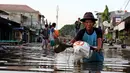 Warga melintasi banjir yang merendam perumahan Villa Mutiara Pluit, Tangerang, Banten, Senin (3/2/2020). Banjir disebabkan jebolnya tanggul sungai di sekitar kawasan tersebut. (merdeka.com/Magang/Muhammad Fayyadh)