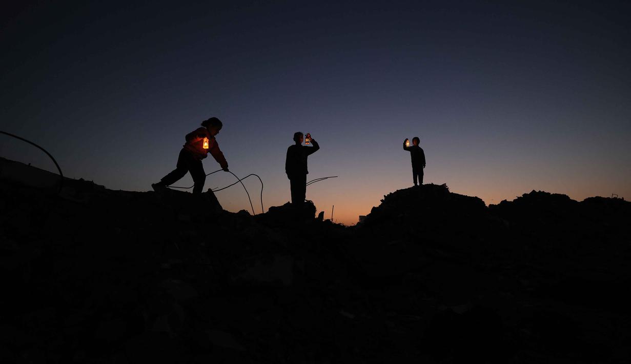 Beberapa pengungsi muda Palestina bermain di reruntuhan bangunan yang hancur di kamp pengungsi Bureij di Jalur Gaza tengah pada 15 Februari 2026. Cahaya lentera Ramadan mulai menerangi malam di kamp-kamp pengungsian warga Palestina di Gaza. (Eyad Baba/AFP)