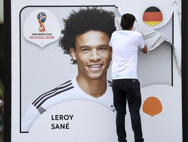 Seorang petugas menurunkan gambar Leroy Sane dari dinding museum sepakbola di Dortmund, (4/6/2018). Pelatih Joachim Low tidak memasukan nama Leroy Sane dalam skuat Der Panzer untuk Piala Dunia 2018. (Federico Gambarini/dpa via AP)
