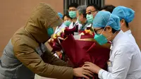 Pasien yang dinyatakan sembuh dari virus corona memberi salam perpisahan kepada petugas medis di Rumah Sakit Afiliasi Pertama Universitas Zhengzhou, Provinsi Henan, China, Selasa (4/2/2020). Ini adalah pasien pertama yang dinyatakan sembuh dari virus corona di Shaanxi. (Xinhua/Liu Xiao)