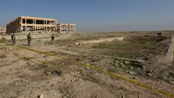 Pasukan Kurdi berdiri di sekitar kuburan massal yang diduga lokasi makam anggota Yazidi Irak di pinggiran kota Sinjar, 30 November 2015. Pasukan Kurdi menemukan kuburan ini usai berhasil merebut kembali kota Irak dari militan ISIS. (Reuters/Ari Jalal)