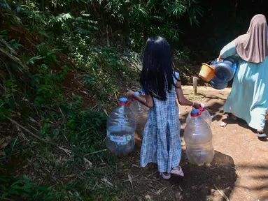 Seorang anak menemani ibunya Warga mengambir air dari satu-satunya sumber mata air di di Kampung Cijaura, Desa Cidokom, Bogor, Jawa Barat, Minggu (26/07/2026). (KLY/ Arie Basuki)