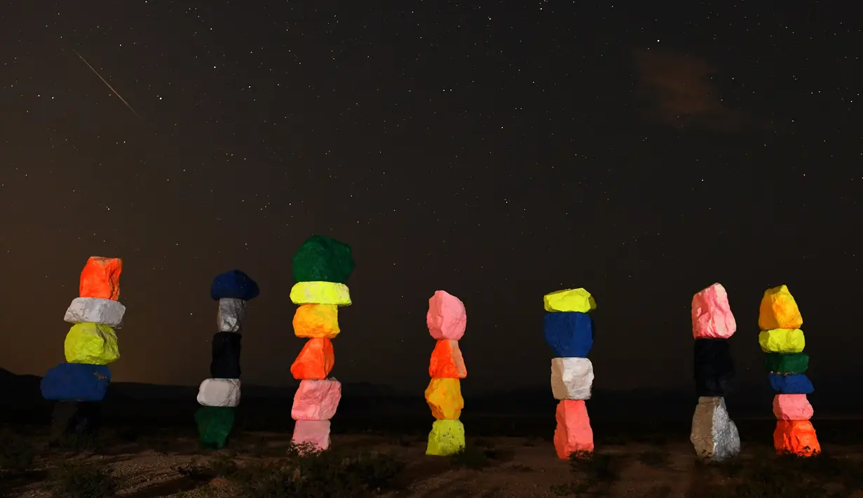 Meteor Perseid melintasi langit di atas instalasi seni "Seven Magic Mountains" dekat Jean, Nevada (13/8). Instalasi seni Seven Magic Mountains terdiri dari tujuh pilar batu-batu berwarna yang ditumpuk lebih dari 30 kaki tingginya. (AFP Photo/Ethan Miller)
