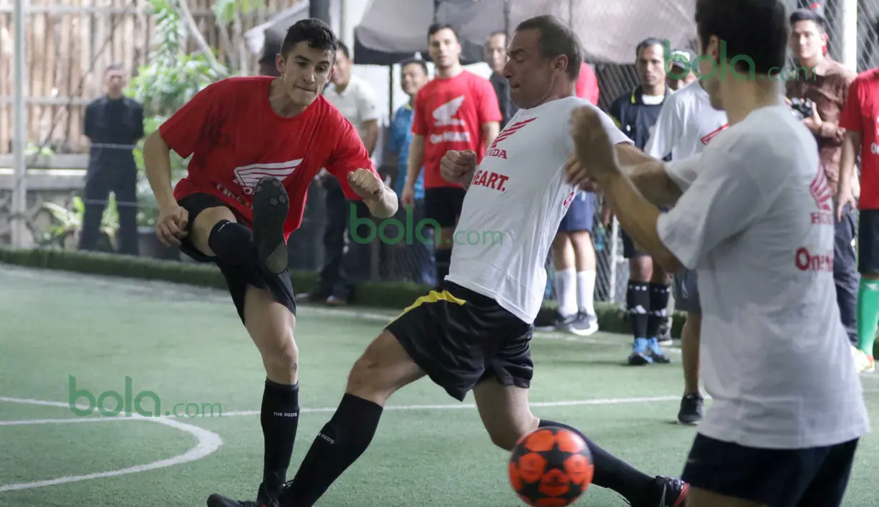 Marc Marquez (kirih) dari Tim Merah melepaskan tembakan saat dihadang Dani Pedrosa (kanan) di Lapangan Futsal Kuningan Village, Jakarta, Sabtu (13/2/2016). (Bola.com/Nicklas Hanoatubun)