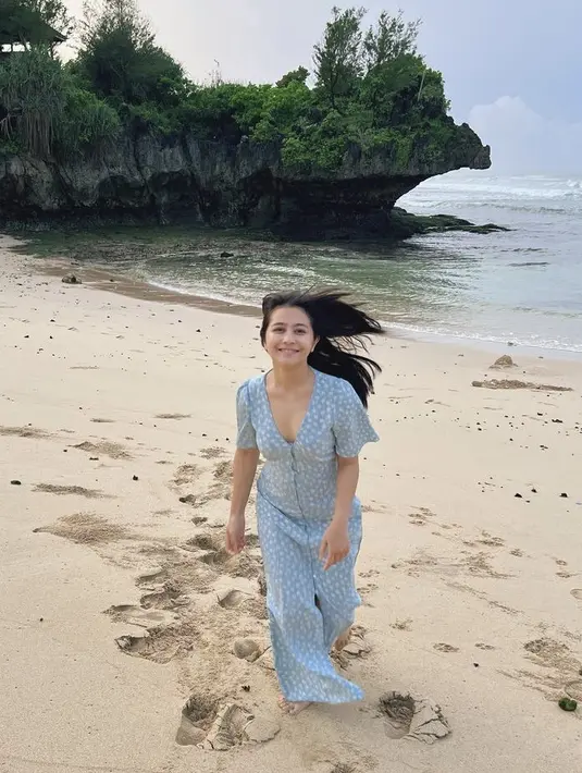 Dress panjang warna biru dengan kerah v neck warna biru juga dikenakan oleh Prilly saat bermain di pantai. (@prillylatuconsina96)