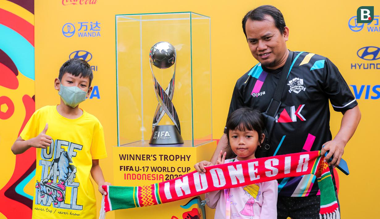 Warga dengan antusias berfoto bersama trofi Piala Dunia U-17 2023 saat Hari Bebas Kendaraan Bermotor di kawasan Bundaran HI, Minggu (15/10/2023). (Bola.com/Bagaskara Lazuardi)