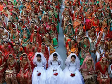 Pengantin perempuan duduk bersama saat nikah massal di Surat, India, Minggu (23/12). Nikah massal bagi perempuan yatim ini digelar oleh pengusaha berlian asal India, Mahesh Savani. (AP/Ajit Solanki)