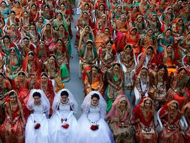 Pengantin perempuan duduk bersama saat nikah massal di Surat, India, Minggu (23/12). Nikah massal bagi perempuan yatim ini digelar oleh pengusaha berlian asal India, Mahesh Savani. (AP/Ajit Solanki)