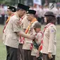 Presiden Joko Widodo memberi tanda kehormatan kepada seorang anak saat perayaan hari jadi Pramuka yang ke-57 di Lapangan Gajah Mada, Wiladatika, Cibubur, Jakarta, Selasa (14/8). (Liputan6.com/Faizal Fanani)