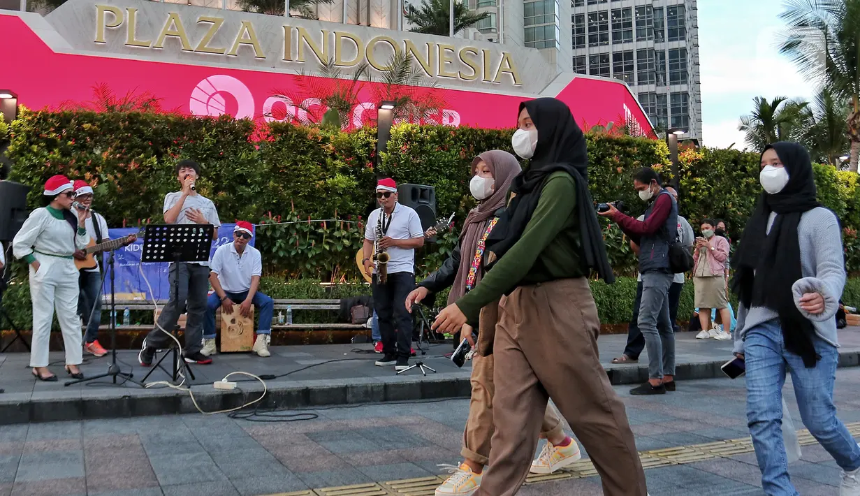 Musisi mengelar pertunjukan musik bernuansa Natal di jalur Pedestrian Bundaran HI, Jakarta Pusat, Selasa (20/12/2022). Pergelaran musik bernuansa Natal tersebut sebagai bentuk pertunjukan untuk menghibur warga yang melintas di Kawasan itu. (Liputan6.com/Angga Yuniar)
