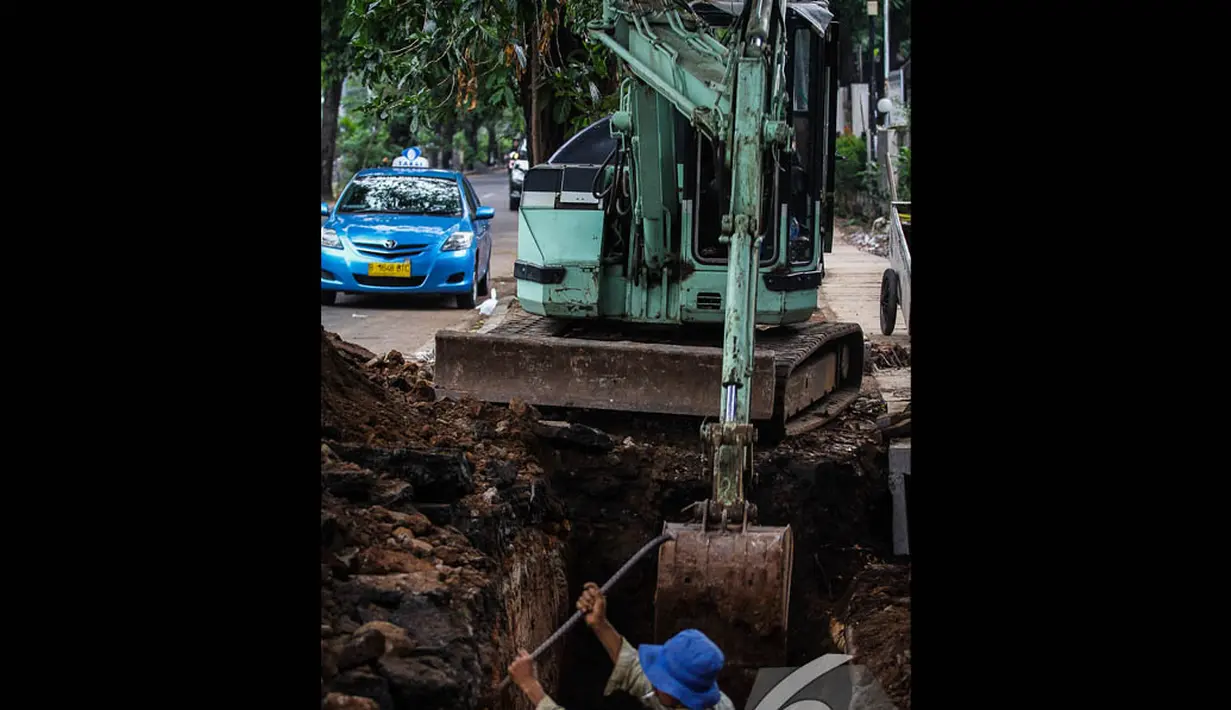 Seorang pekerja dibantu alat berat mengeruk saluran air di Jalan Latuharhari, Jakarta, Jumat (14/11/2014). (Liputan6.com/Faizal Fanani)