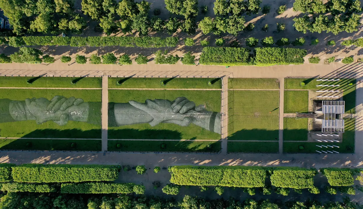 Foto udara dari lukisan raksasa "Beyond Walls" karya seniman jalanan Prancis, Saype, yang terbentang di halaman Champs de Mars, depan Menara Eiffel di Paris, 13 Juni 2019. Menggunakan cat ramah lingkungan, lukisan itu bergambar seperti tangan-tangan raksasa saling bergandengan. (Eric FEFERBERG/AFP)
