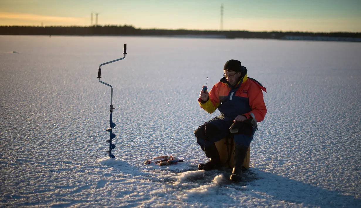 Seorang pria berusaha memancing ikan di laut Bothnia yang sedang membeku, Vaasa, Finlandia (29/12). Kebiasaan memancing di laut beku merupakan hal menantang yang ditunggu-tunggu oleh sebagian warga setempat. (AFP PHOTO/Olivier Morin)