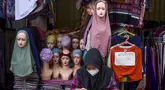 Seorang pedagang menggunakan telepon seluler pintarnya sambil menunggu pelanggan di sebuah kios pinggir jalan di Jakarta pada 30 Juni 2025. (BAY ISMOYO/AFP)