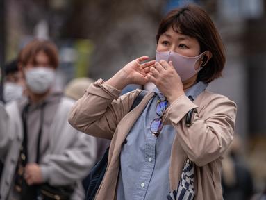 Orang-orang menyeberang jalan di distrik Shibuya Tokyo pada hari pertama pemerintah Jepang mencabut ketentuan wajib mengenakan masker, Senin (13/3/2023). Sebelumnya selama tiga tahun terakhir Jepang mewajibkan pemaikaian masker akibat pandemi Covid-19. (Photo by Yuichi YAMAZAKI / AFP)