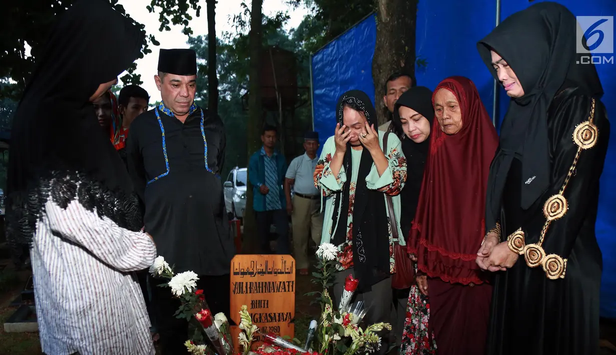 Suasana saat Ibu Julia Perez, Sri Wulansih beserta keluarga ziarah ke makam Julia Perez di TPU Pondok Ranggon, Jakarta, Selasa (13/6). Setelah mendoakan, Sri Wulansih beserta keluarga menaburkan bunga di makam Jupe. (Liputan6.com/Herman Zakharia)